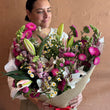 Load image into Gallery viewer, Person holding a large bouquet of flowers against a beige wall

